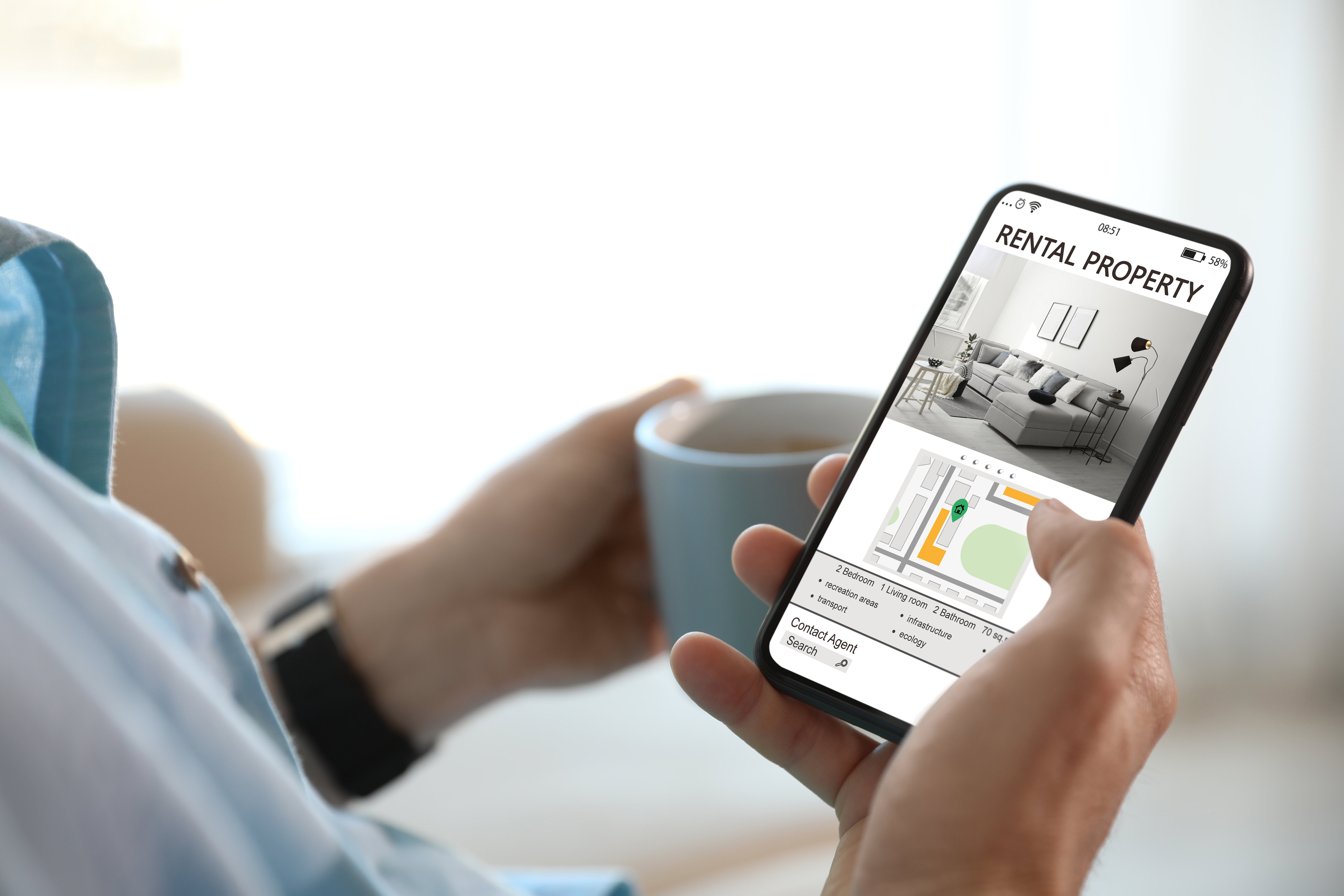 A user viewing a rental property listing on a cell phone while drinking a cup of coffee.