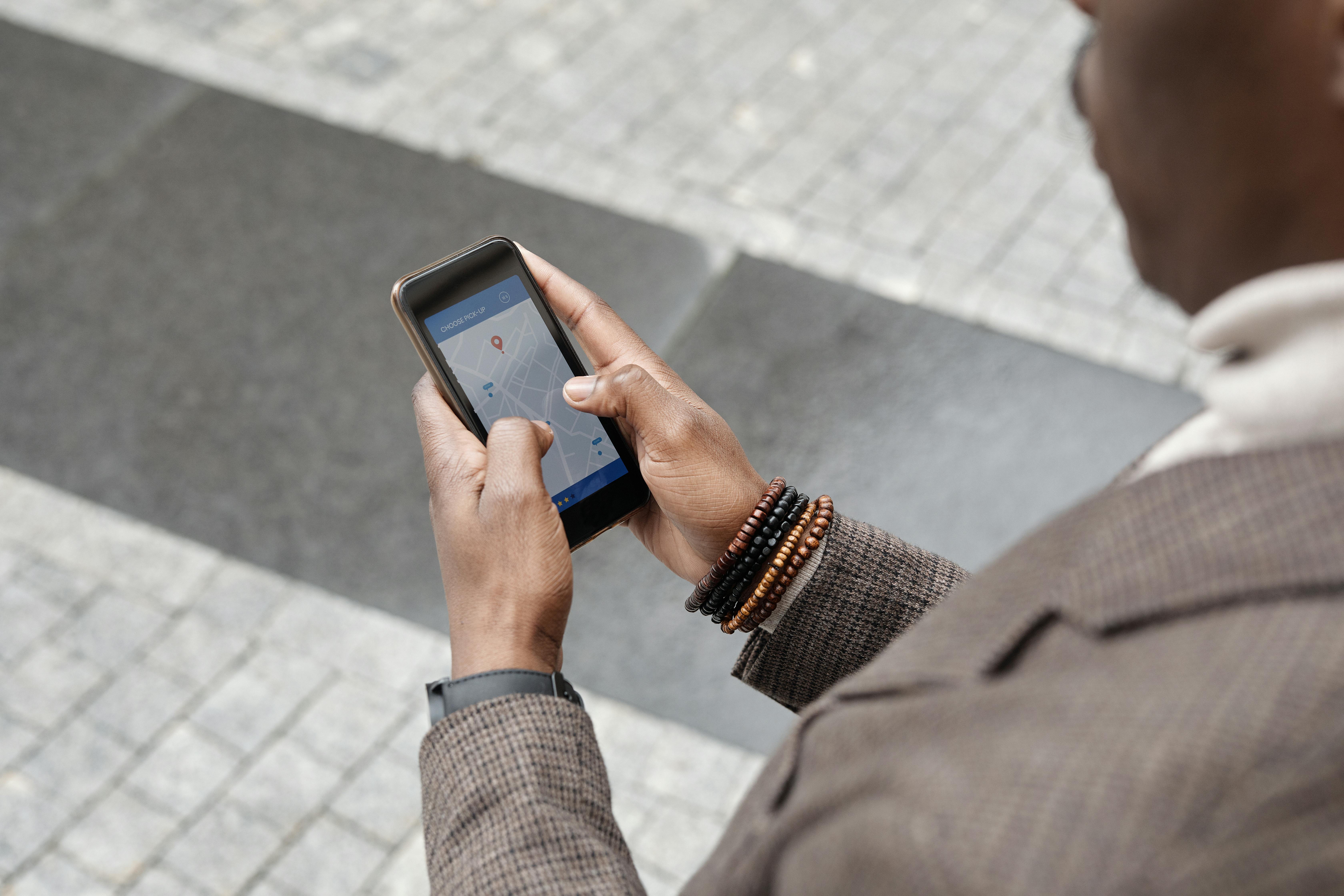 A man on a sidewalk looking up the location of a business on his phone.
