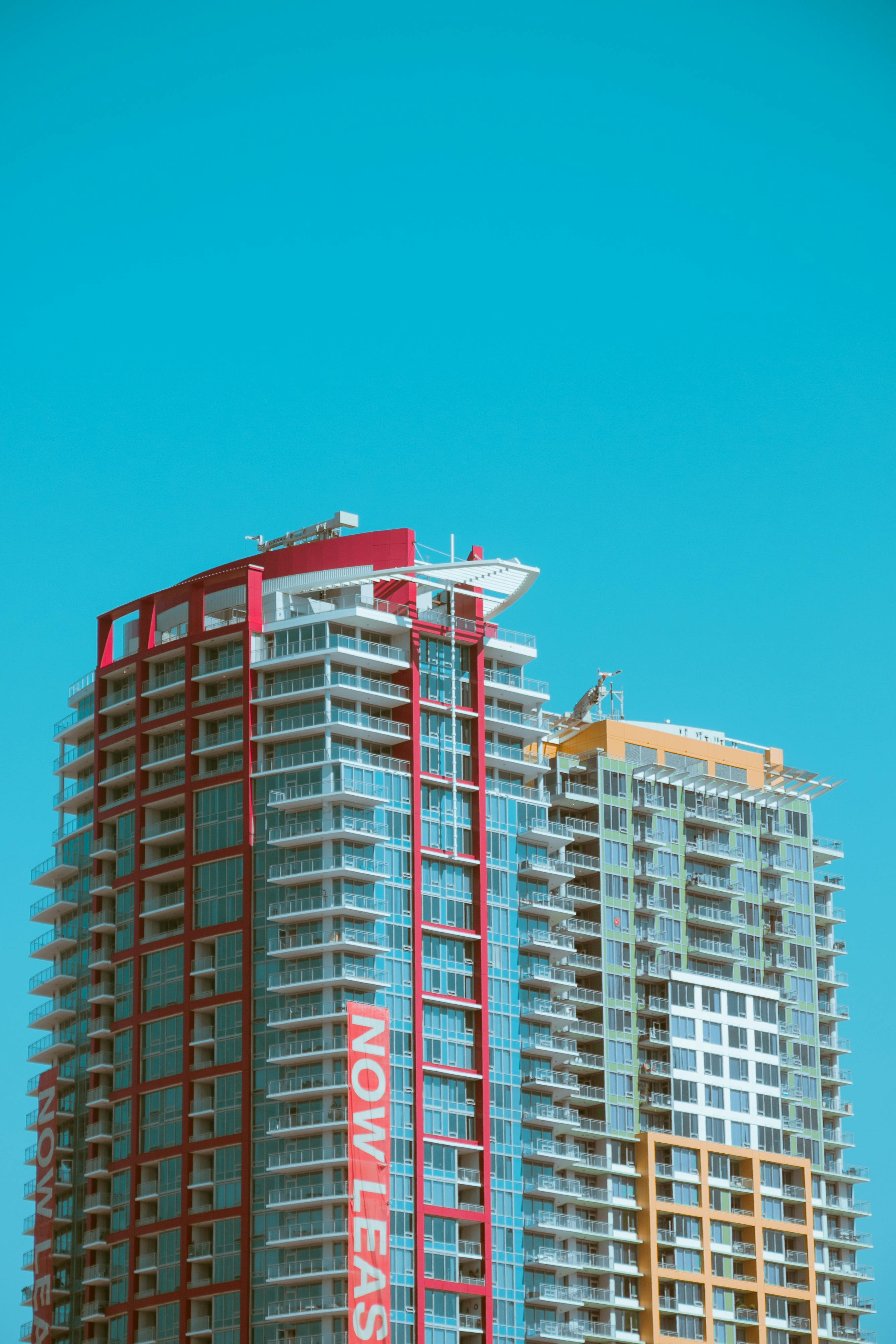 A high rise apartment building in San Diego, CA, with a "Now Leasing" banner draped down the side of it.