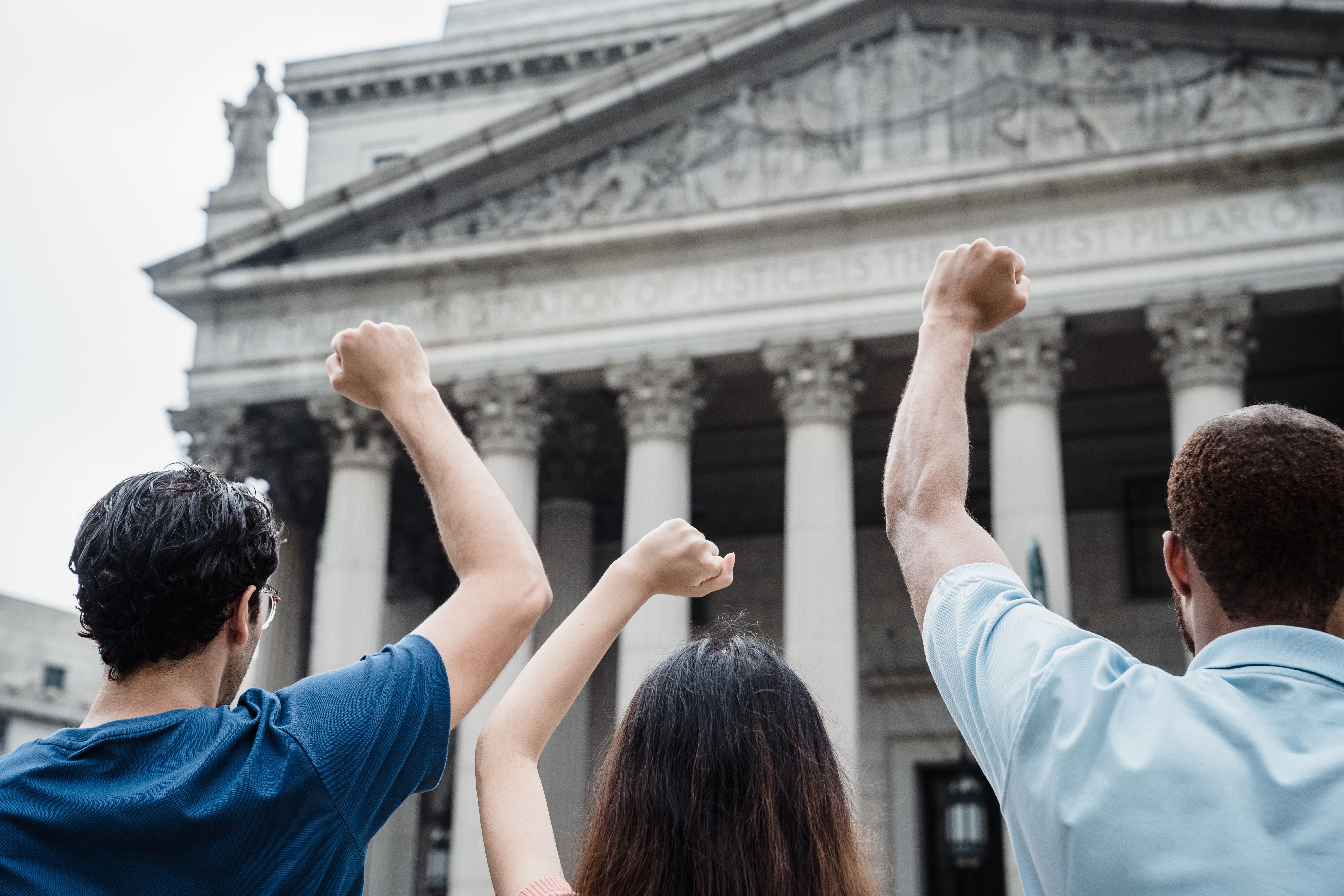 A group of people protesting outside a courthouse.