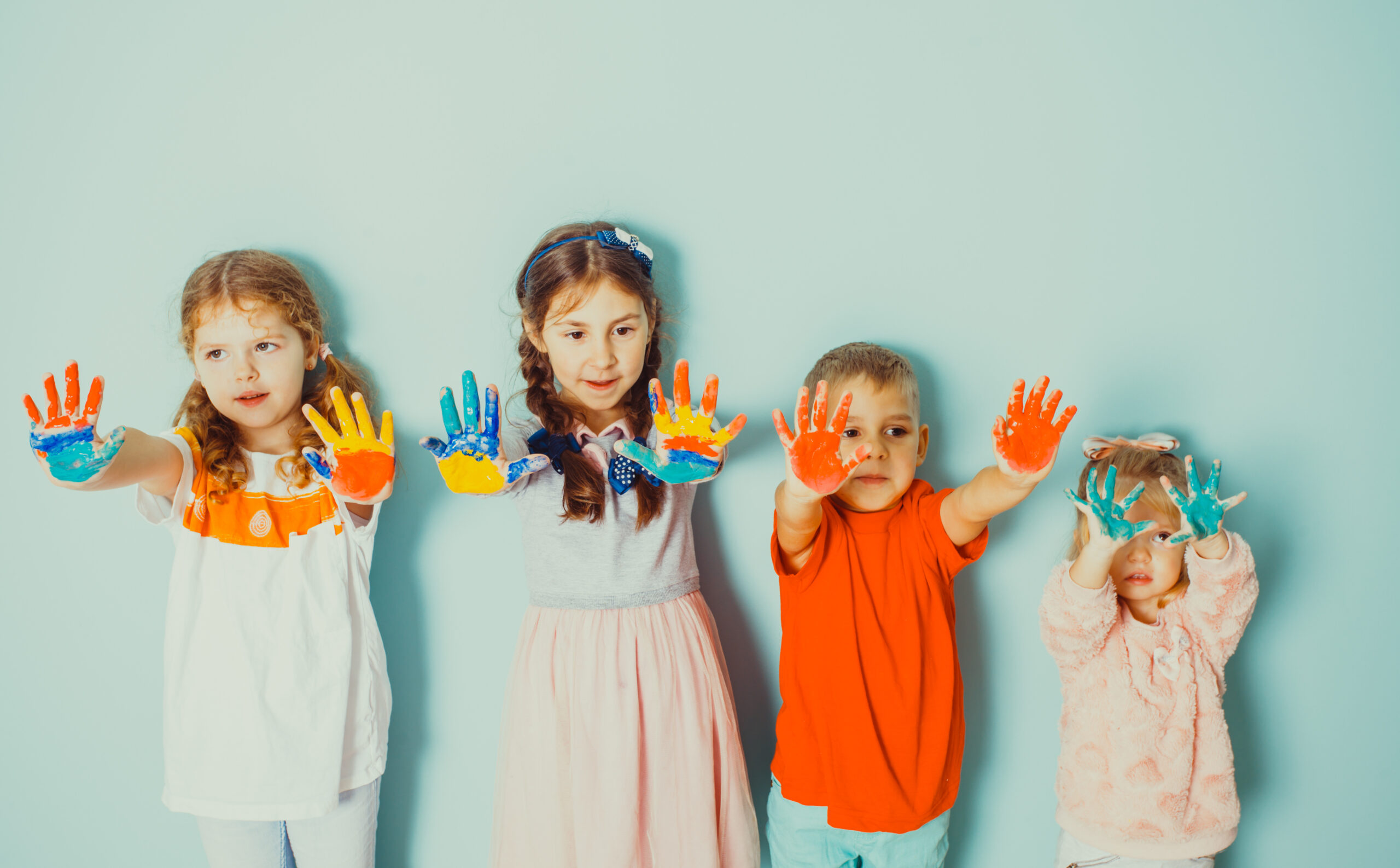 kids showing their painted colorful hands to the camera